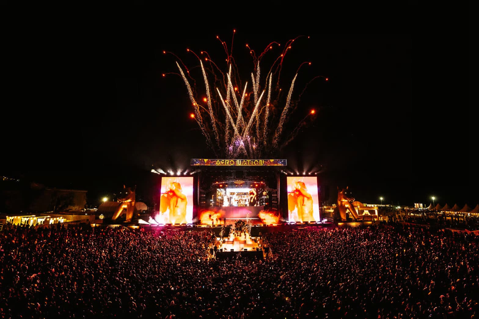 Fireworks above the Afro Nation main stage at night, over a crowd filling the field.