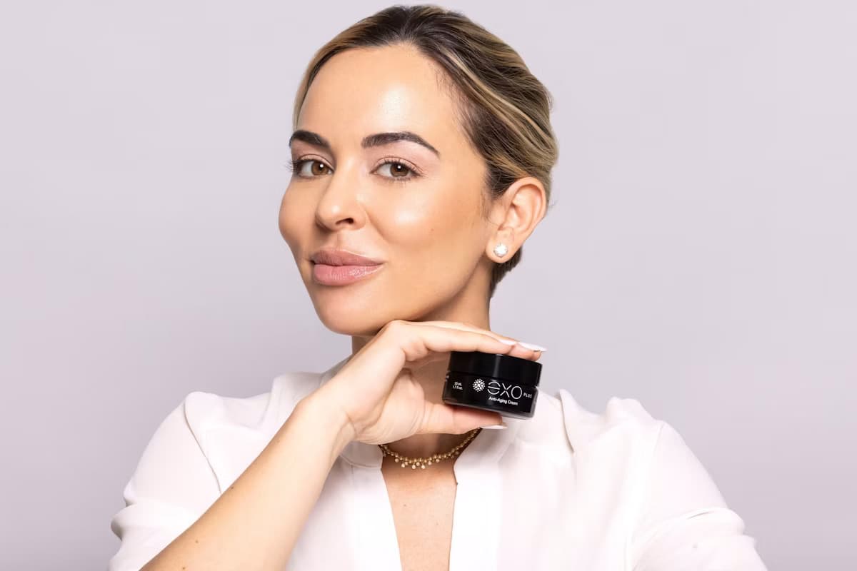 Dr. Nicole Martin holding an EXO PLUS jar against a pale studio background.