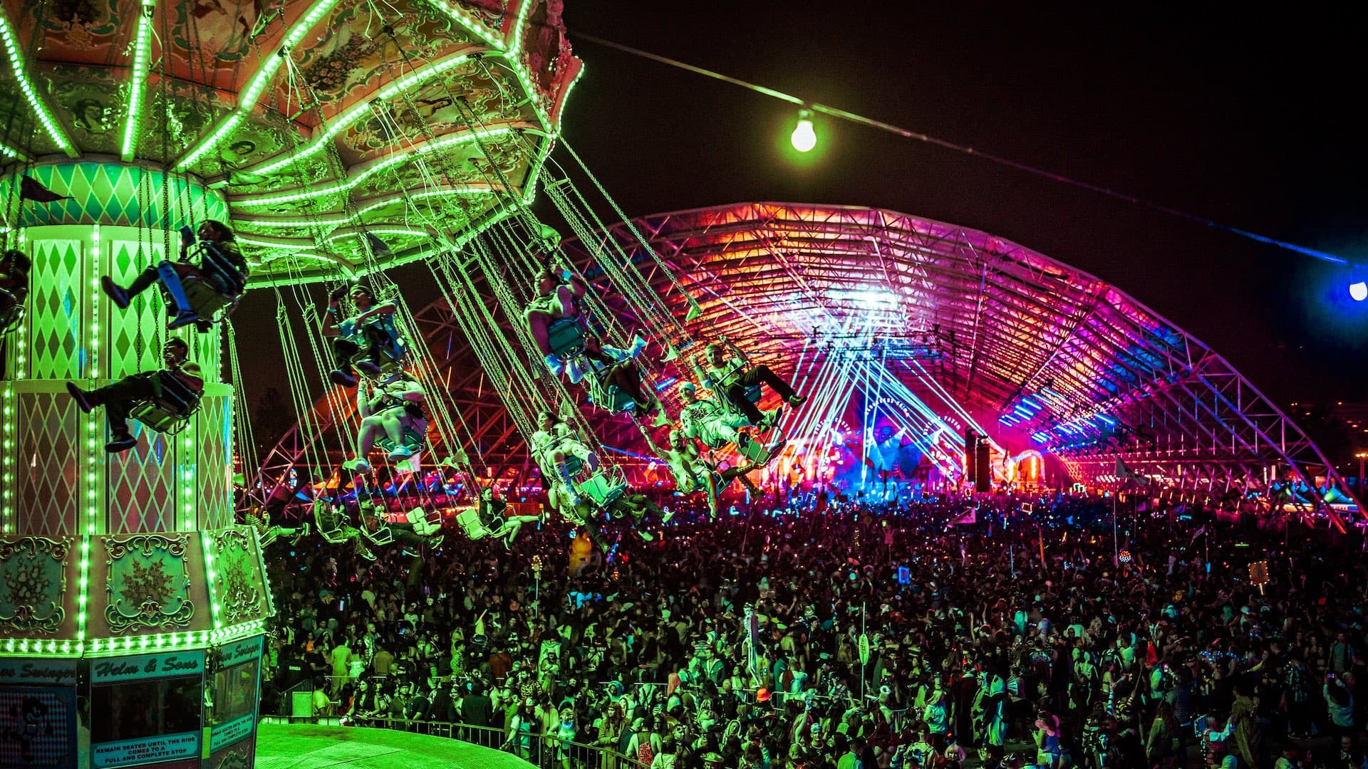Festival swing ride illuminated above the crowd at night